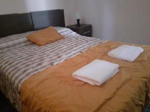 Una cama con dos toallas blancas encima. en Posta Malbec en Las Compuertas