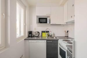 a white kitchen with a sink and a microwave at Norden Homes Quick & Easy Airport and City Centre Access in Helsinki