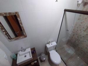 een badkamer met een toilet, een wastafel en een spiegel bij Residencial Pérola - Localizado entre a Pinheira e a Guarda do Embaú in Guarda do Embaú