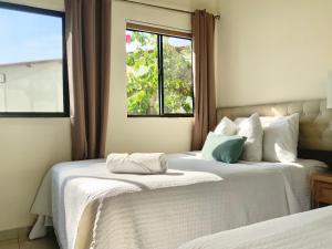 two beds in a room with a window at Paradise Surf Hotel in San Miguel