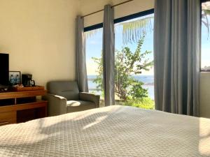 a bedroom with a bed and a chair and a window at Paradise Surf Hotel in San Miguel
