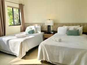 a bedroom with two beds with white sheets and a window at Paradise Surf Hotel in San Miguel