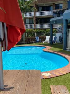 Una gran piscina azul con una sombrilla roja en Bribie Waterways Motel, en Bongaree 63 fotos más