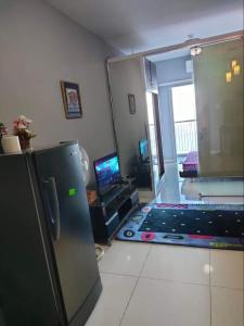 ein Wohnzimmer mit einem Kühlschrank und einem TV in der Unterkunft Taal Haven at SMDC Wind Residences Tagaytay in Tagaytay