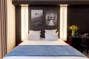 una camera da letto con un grande letto con cuscini bianchi di Best Western St Exupery Bordeaux Ouest a Eysines
