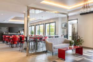 un restaurante con un bar con mesas y sillas rojas en Best Western St Exupery Bordeaux Ouest, en Eysines