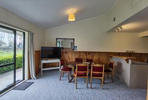 ein Esszimmer mit einem Tisch, Stühlen und einem TV in der Unterkunft Mystery Creek Motel in Hamilton