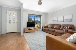 a living room with a couch and a flat screen tv at Serenity Now Inverloch in Inverloch