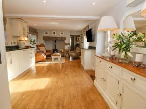 Una cocina con gabinetes blancos y una sala de estar. en Farmhouse, en Pwllheli