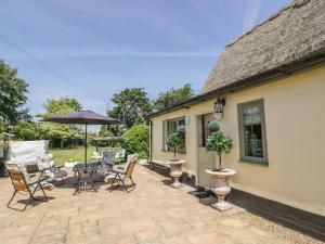 a patio with chairs and an umbrella next to a house at Waveney Cottage in Diss