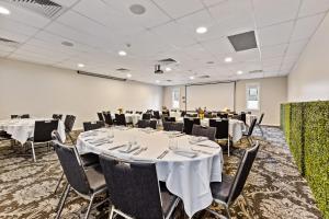 a conference room with tables and chairs and a projection screen at International Hotel Wagga Wagga in Wagga Wagga