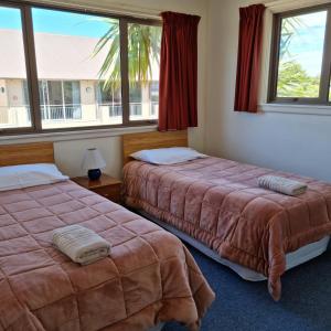 two beds in a room with two windows at Methven Motel & Apartments in Methven