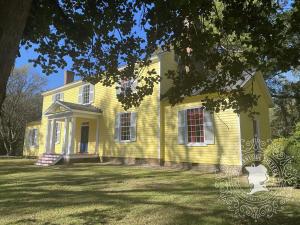 a yellow house with a large yard in front of it at The Sunnyside Sisters Bed and Breakfast in Clarksville