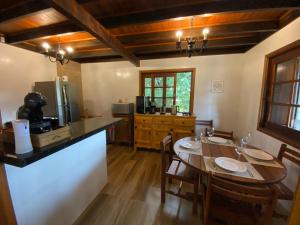 a dining room with a table and a kitchen at Chalé Uirapurus in Monte Verde