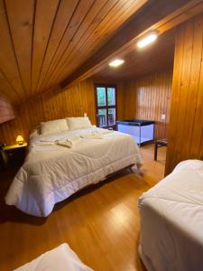 a bedroom with two beds and a wooden wall at Chalé Uirapurus in Monte Verde