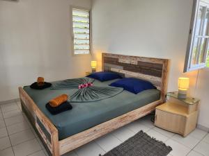 een slaapkamer met een groot houten bed met blauwe kussens bij Villa JADE, VUE MER, PISCINE PRIVEE, PLAGE A PIEDS in Le Gosier +95 foto's