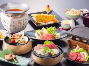 uma mesa coberta com diferentes tipos de alimentos em pratos em Kyukamura Nanki-Katsuura em Nachikatsuura