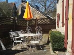 un tavolo e sedie con un ombrellone in un patio di Maison du XVe restaurée avec cheminée, jardin clos et bar privé - FR-1-410-127 a Crannes-en-Champagne
