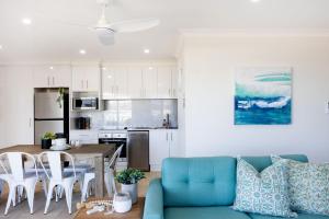 Una sala de estar con un sofá azul y una mesa. en Mariners 3, en Mollymook