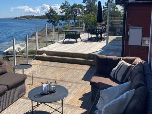 a wooden deck with couches and tables and the water at Holiday home OSKARSHAM III in Oskarshamn