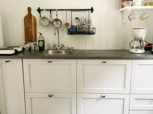 una cocina con armarios blancos y fregadero en Holiday home ÖDEBORG, en Herräng