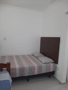 Bett in einem Zimmer mit einer weißen Wand in der Unterkunft Quitinete para temporada em Cabo Frio in Cabo Frio