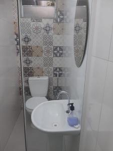 a bathroom with a white sink and a toilet at Quitinete para temporada em Cabo Frio in Cabo Frio