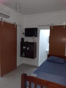1 dormitorio con 1 cama y TV de pantalla plana en Quitinete para temporada em Cabo Frio, en Cabo Frío