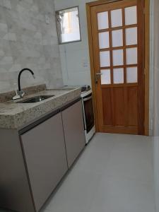 a kitchen with a sink and a wooden door at Quitinete para temporada em Cabo Frio in Cabo Frio