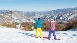 two people standing on top of a snow covered mountain at Kyukamura Norikura-Kogen in Matsumoto