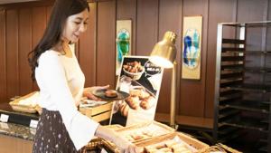 kobieta trzymająca talerz jedzenia w piekarni w obiekcie Kyukamura Minami-Izu w mieście Minamiizu
