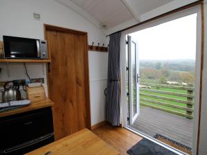 a kitchen with a sliding glass door with a balcony at Shepherds Cabin at Titterstone in Farden +12 photos