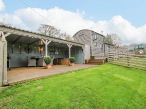 a backyard with a wooden deck and a house at Shepherds Cabin at Titterstone in Farden