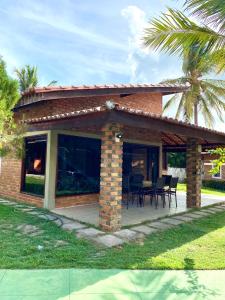 ein Backsteinhaus mit einer Terrasse mit Tischen und Stühlen in der Unterkunft Barreirinhas - Casa no Condomínio dos Jipeiros in Barreirinhas