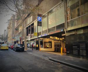 una calle de la ciudad con coches estacionados frente a los edificios en CitiClub Hotel Melbourne, en Melbourne