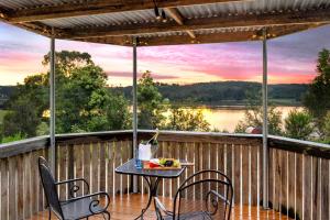 einen Tisch und Stühle auf einer Terrasse mit Seeblick in der Unterkunft Sunset Cottage - Yarra Valley in Healesville