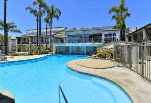 a swimming pool in front of a building with palm trees at 7 Heaven in Mandurah