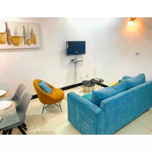 sala de estar con sofá azul, sillas y TV en Suite Grace en Libreville