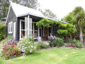 una piccola casa con fiori in cortile di Warm Earth Cottages a Aongatete