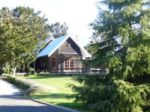 una grande casa con un tetto a padiglione su un cortile verde di Warm Earth Cottages a Aongatete