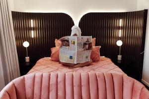 Un dormitorio con una cama rosa con un periódico. en NEW! Dacha on Maggie No#2, Unrivaled Island Luxury en Nelly Bay