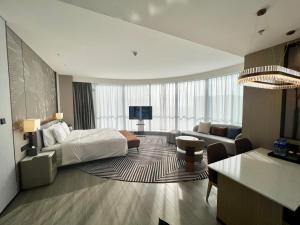 um quarto de hotel com uma cama e uma sala de estar em Wanda Jin Xiaohe Xincheng em Taiyuan