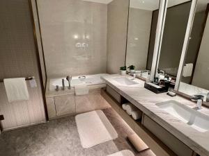 a bathroom with two sinks and a tub and a shower at Wanda Jin Xiaohe Xincheng in Taiyuan