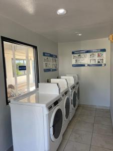 a laundry room with three washing machines and a window at Motel 6 Denton, TX - UNT in Denton