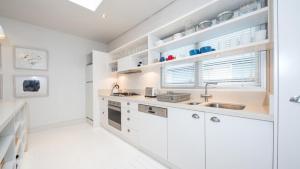 a white kitchen with white cabinets and a sink at Pearl Beach House in Pearl Beach