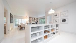 a white kitchen with a counter with plates and dishes at Pearl Beach House in Pearl Beach