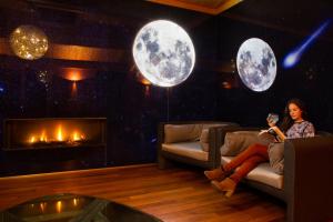 a woman sitting on a couch in a room with three moon panels at Hotel Els Caçadors de Ribes in Ribes de Freser