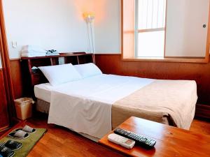 1 dormitorio con cama y mesa con mando a distancia en Hotel Harbor, en Agena
