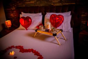 Una cama con dos corazones rojos y una mesa con una vela en Chale em Curitiba - Chales Portugal, en Campo Magro