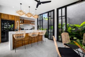 a kitchen with a bar with chairs and windows at Villa Hammock by BaliSuperHost in Ubud +13 photos